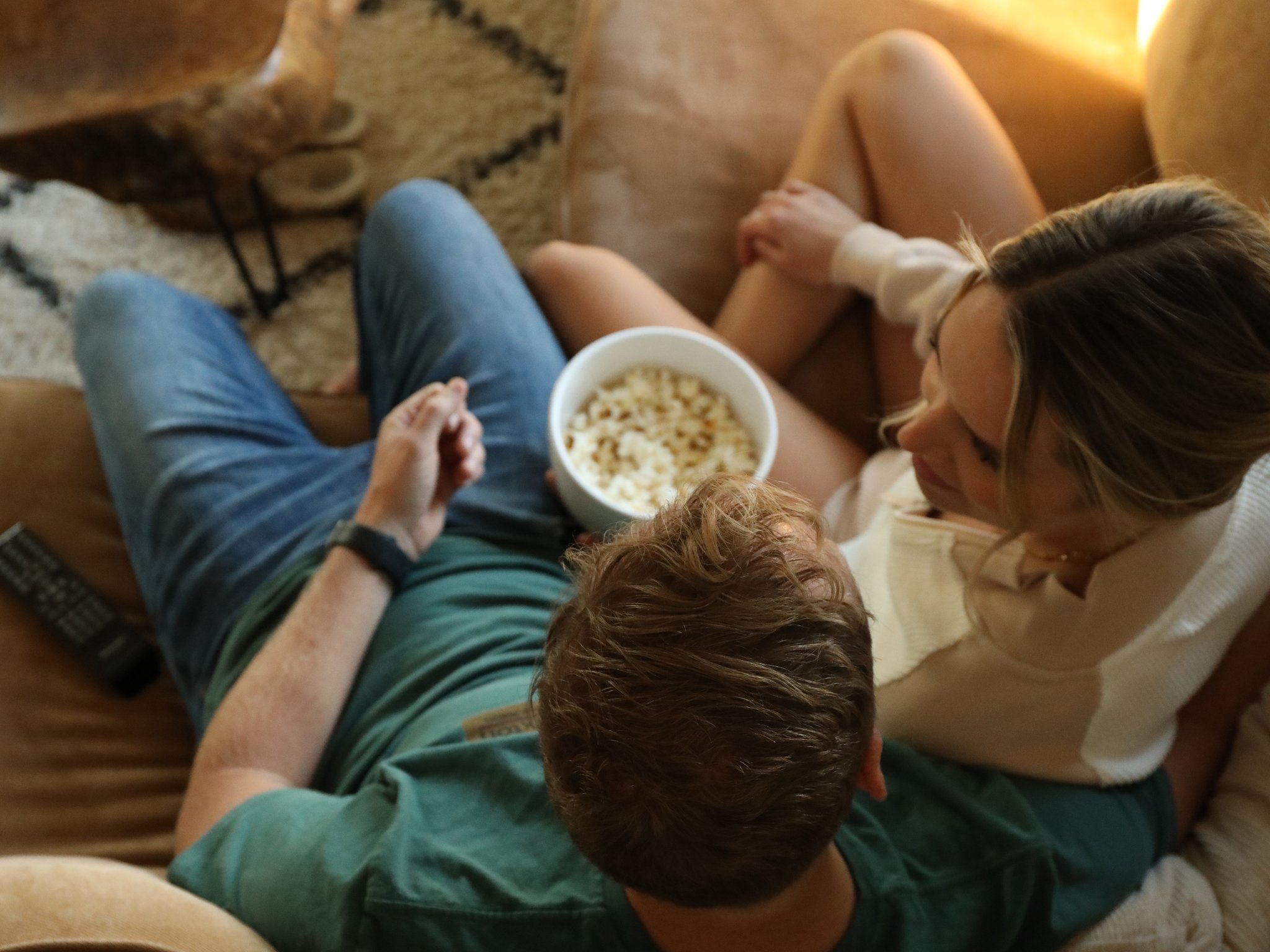 Man and woman eating popcorn on a couch